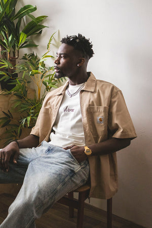 Model sitting wearinf carhartt wip short sleeve shirt and jeans