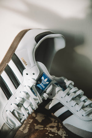 adidas Originals samba trainers in white stacked up against the wall 