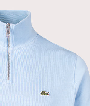 Lacoste Quarter Zip Croc Logo Sweatshirt in HBP Pale Blue, 100% Cotton. At EQVVS Menswear. Front logo shot