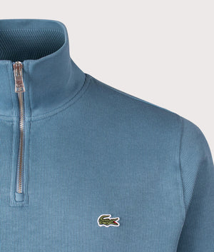 Lacoste Quarter Zip High Neck Interlock Sweatshirt in Limestone. Shot at EQVVS. Detail shot. 