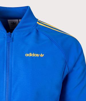 adidas Originals SST Track Top in Blue at EQVVS. Detailed logo shot. 