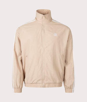 The adidas Originals Firebird Track Top in Magic Beige. Front angle shot at EQVVS.
