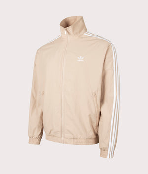 The adidas Originals Firebird Track Top in Magic Beige. Side angle shot at EQVVS.