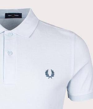 Fred Perry Polo Shirt in Light Ice/ Petrol Blue, 100% Cotton at EQVVS. Logo detail shot. 