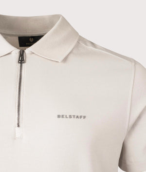 Belstaff Alloy Polo Shirt in Stone Beige. Shot at EQVVS.  Detailed logo shot. 