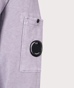 C.P. Company Lens Sleeve Crewneck Sweatshirt in Lavander Violet, 100% cotton at EQVVS. Lens shot. 