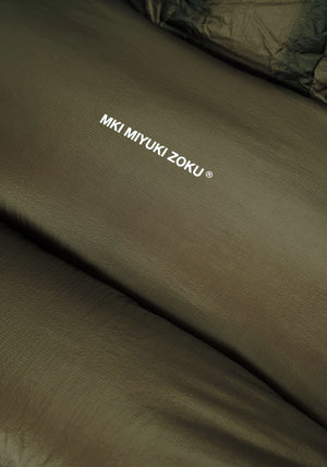 MKI MIYUKI ZOKU Translucent Bubble Jacket in Moss Green at EQVVS Menswear. Logo Detail Shot. 