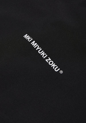 MKI MIYUKI ZOKU Relaxed Fit V2 Shell Hooded Jacket in Black at EQVVS Menswear. Detail Logo Shot.